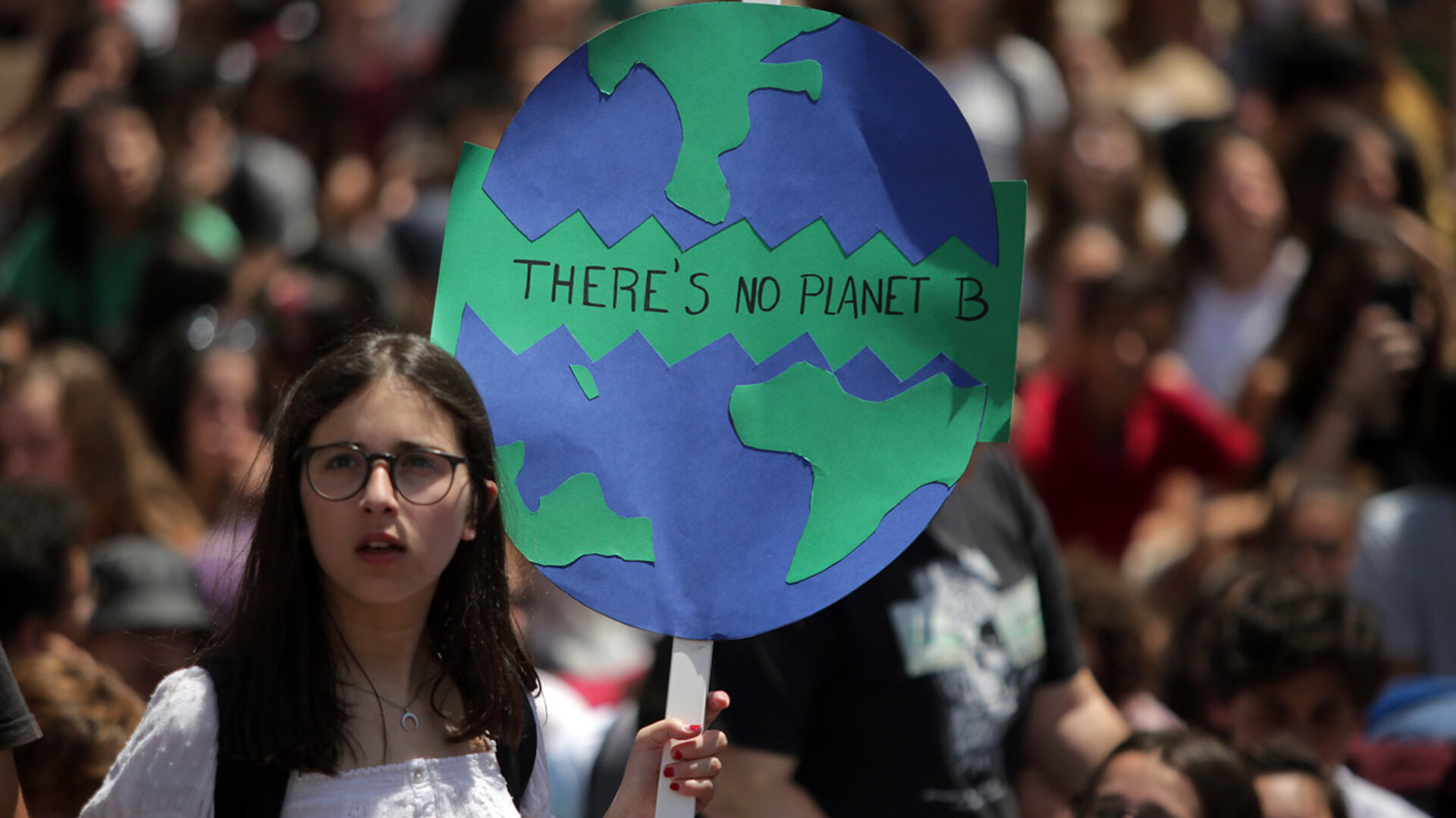 A young protester holds a hand-drawn "There's No Planet B" sign at a climate march