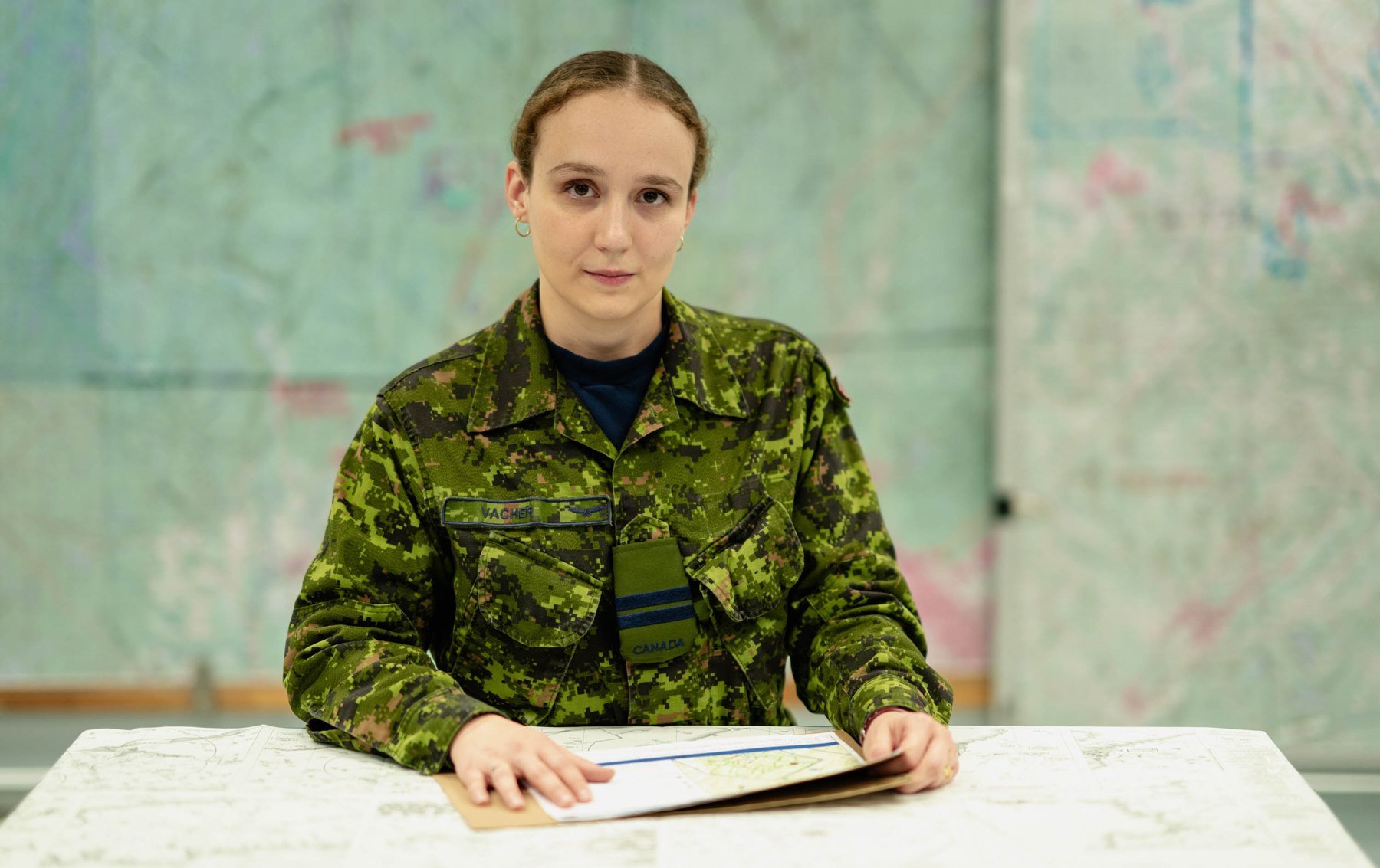 A Canadian Armed Forces officer in CADPAT uniform with operational maps in the background. Photo from the Canadian Forces recruitment site, forces.ca.
