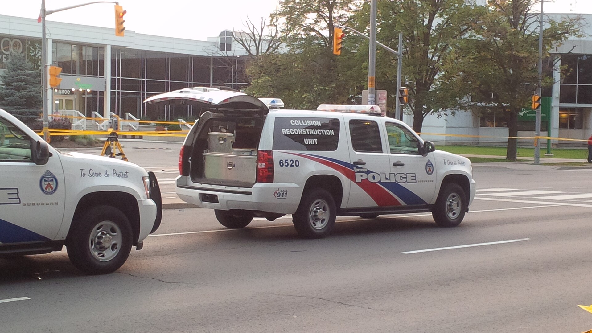 Two Toronto Police vehicles, including a Collision Reconstruction Unit Suburban, parked at a scene with crime-scene tape.